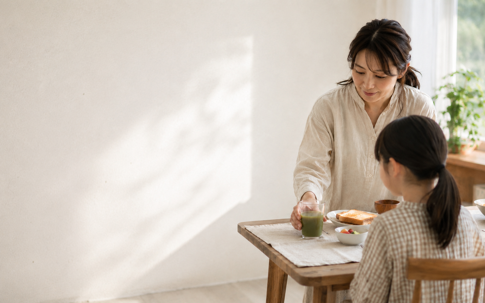 朝食のテーブルでモリンガドリンクを娘に渡す母親