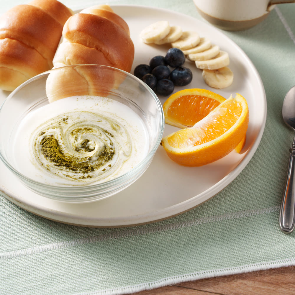パンとフルーツの朝食に、モリンガ青汁をひとさじ加えたヨーグルト